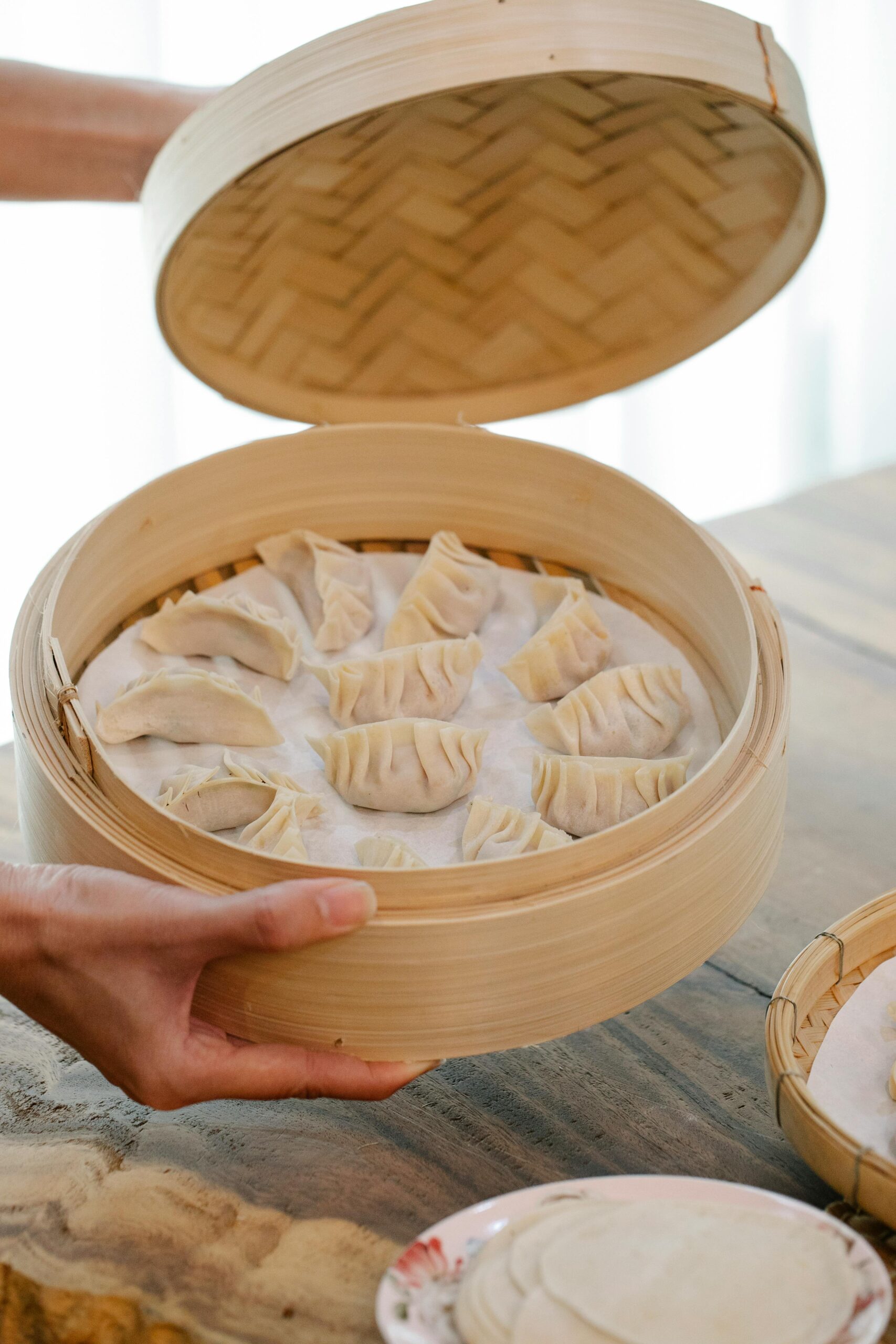 Homemade dumplings placed in a traditional bamboo steamer, ready to be cooked.